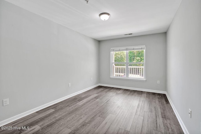 empty room featuring baseboards, visible vents, and dark wood finished floors
