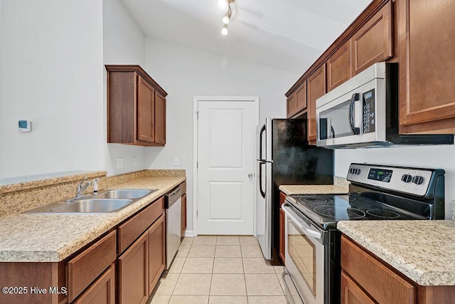 kitchen with appliances with stainless steel finishes, a sink, light countertops, light tile patterned floors, and vaulted ceiling