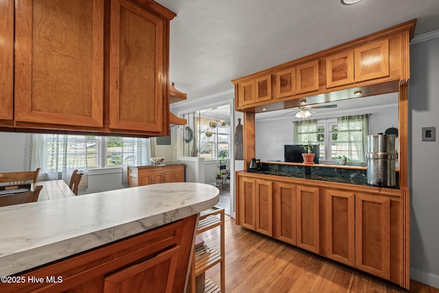 kitchen with ceiling fan, light wood-style floors, and brown cabinets