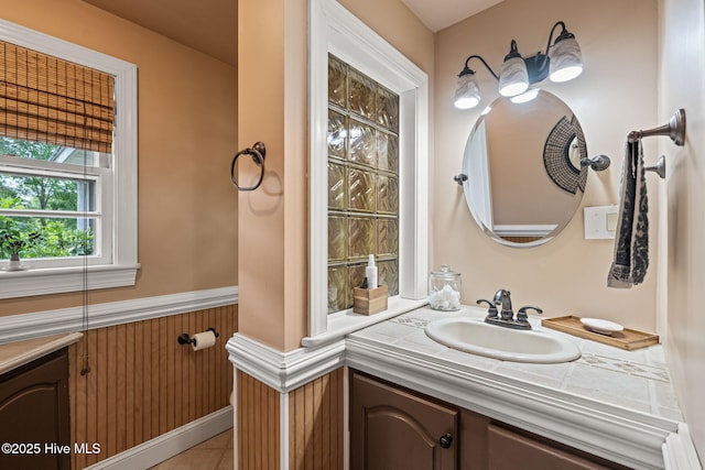 bathroom with tile patterned floors, wainscoting, wood walls, and vanity