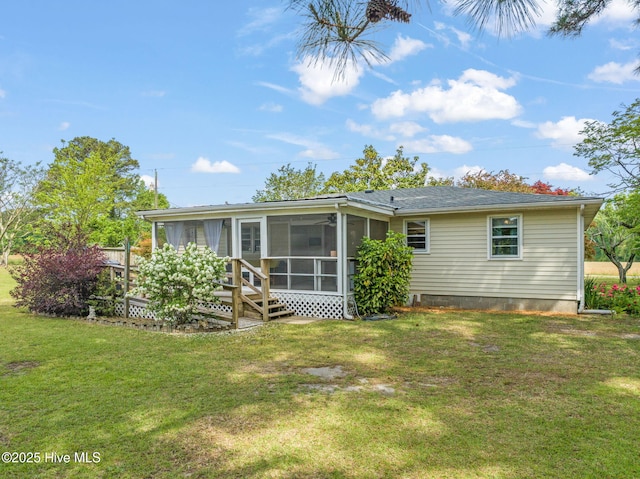 rear view of house featuring a yard and a sunroom