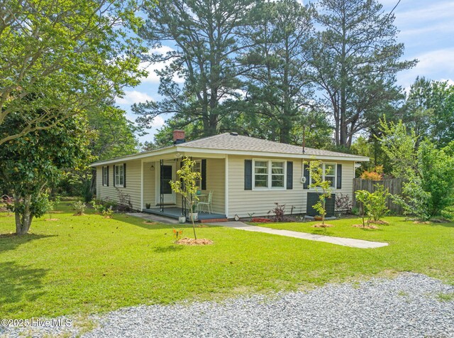 single story home with a porch, a front yard, a chimney, and fence