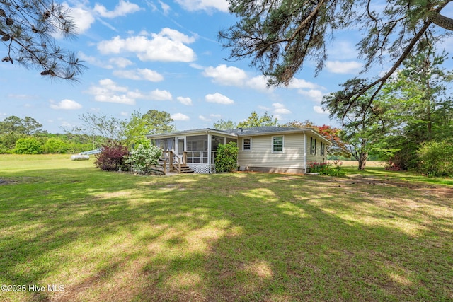 back of property with a sunroom and a yard