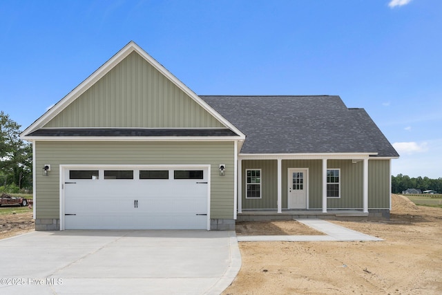 view of front of house with a shingled roof, covered porch, driveway, board and batten siding, and an attached garage