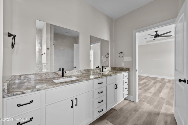 full bathroom featuring double vanity, wood finished floors, ceiling fan, and a sink