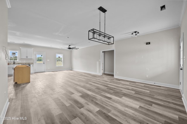 unfurnished living room with crown molding, ceiling fan, baseboards, and light wood-style floors