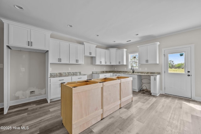 kitchen featuring ornamental molding, a sink, white cabinets, and light wood-style floors