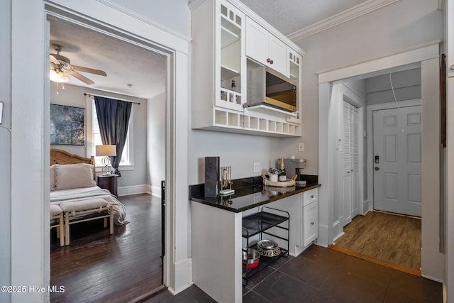 210 S 17th St, Wilmington, NC 28401 - kitchen with dark countertops, glass insert cabinets, white cabinetry, ornamental molding, and a ceiling fan