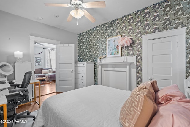 bedroom with wallpapered walls, ceiling fan, and wood finished floors