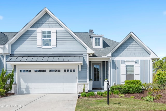 craftsman inspired home with a standing seam roof, a shingled roof, metal roof, an attached garage, and driveway