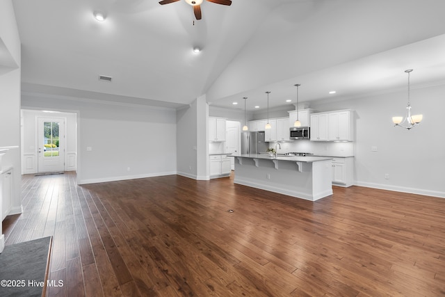 unfurnished living room featuring recessed lighting, a sink, dark wood finished floors, ceiling fan with notable chandelier, and vaulted ceiling