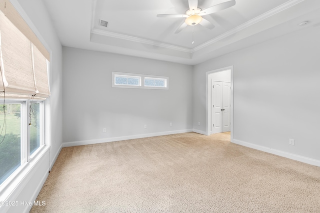 spare room featuring a ceiling fan, a tray ceiling, ornamental molding, and light carpet