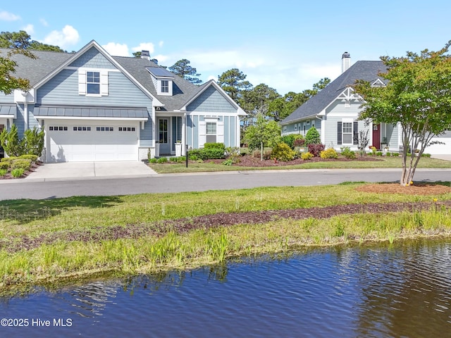 view of front of home with roof with shingles, a standing seam roof, metal roof, a water view, and driveway
