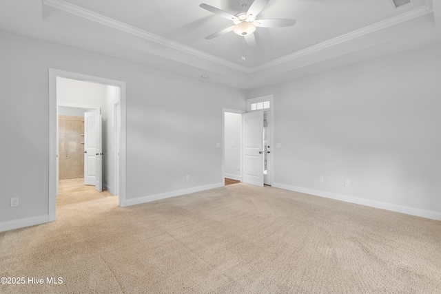 empty room with crown molding, a raised ceiling, a ceiling fan, and carpet flooring