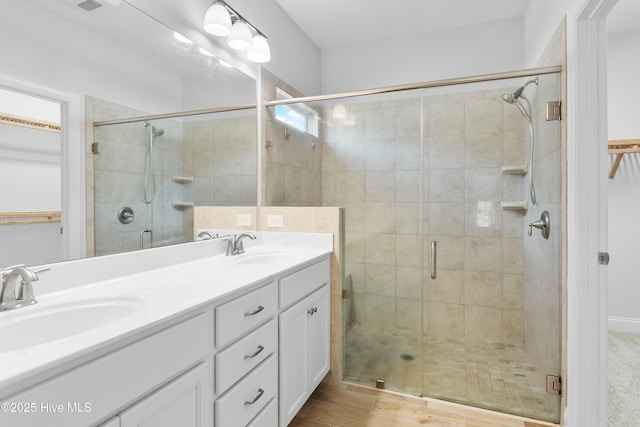 full bath featuring double vanity, a shower stall, and a sink