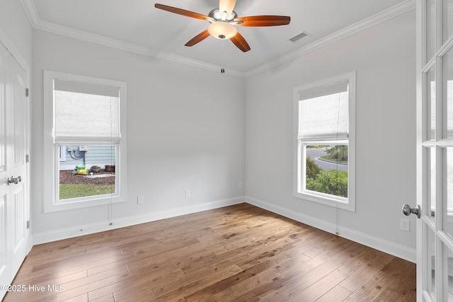 unfurnished room featuring visible vents, ornamental molding, a wealth of natural light, and hardwood / wood-style flooring