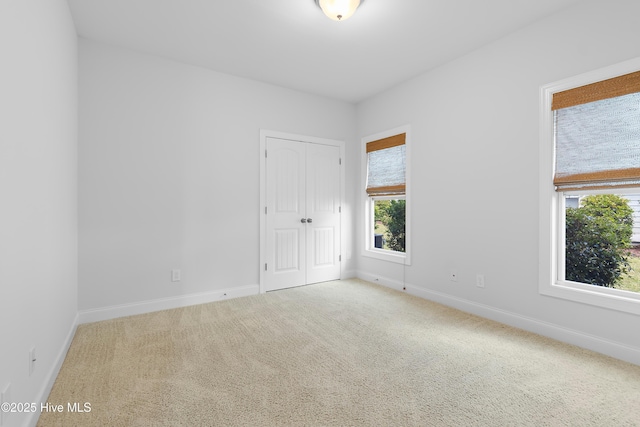 carpeted spare room with baseboards and plenty of natural light