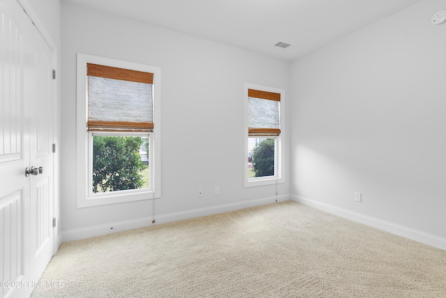 spare room featuring plenty of natural light, carpet, and baseboards