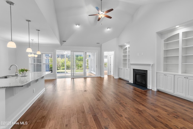 living room with built in features, baseboards, a ceiling fan, and dark wood-style flooring