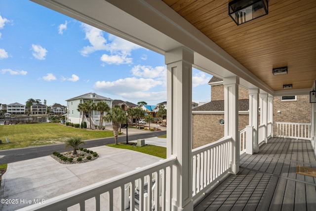 wooden deck with covered porch, a residential view, and a yard