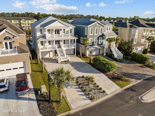 view of front of home with concrete driveway, a balcony, stairs, a residential view, and a garage