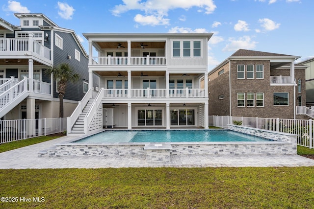 back of property with stairs, a fenced in pool, ceiling fan, a yard, and a fenced backyard