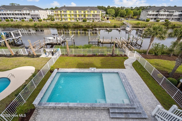 pool with boat lift, a fenced backyard, a water view, and a lawn