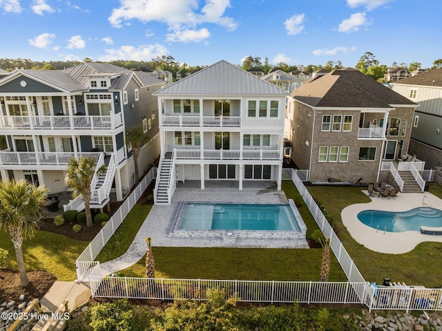 rear view of property with stairs, a balcony, and a fenced backyard