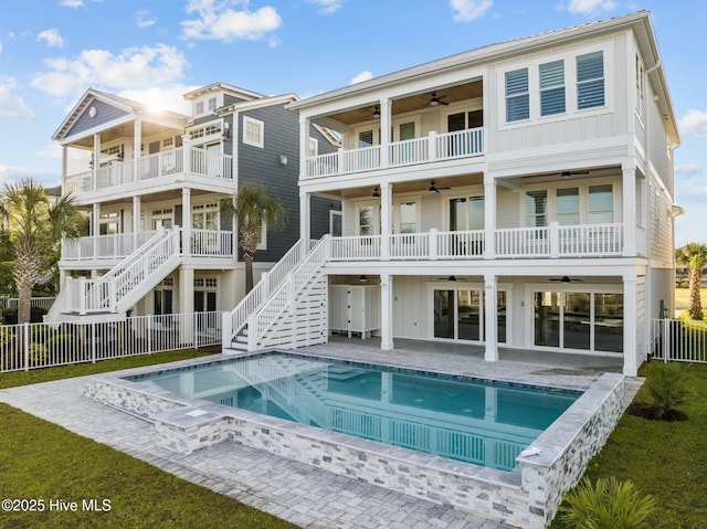 rear view of property featuring a fenced in pool, ceiling fan, fence private yard, and board and batten siding