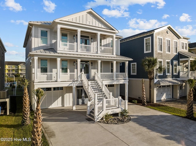 beach home featuring covered porch, board and batten siding, concrete driveway, and a garage