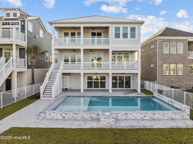 rear view of house featuring board and batten siding, a fenced backyard, stairway, ceiling fan, and a hot tub