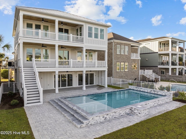 rear view of house with board and batten siding, stairs, a fenced in pool, ceiling fan, and a fenced backyard