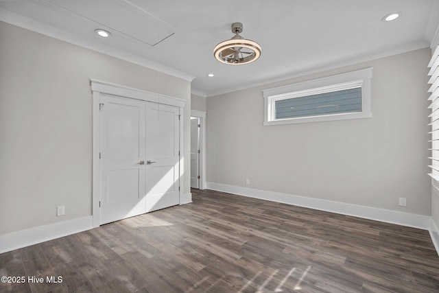 unfurnished bedroom with attic access, ornamental molding, dark wood-style floors, and baseboards