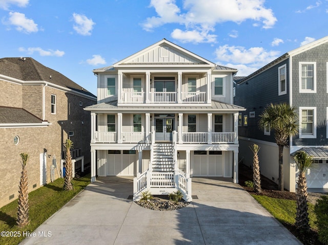 beach home with board and batten siding, covered porch, a standing seam roof, a garage, and stairs