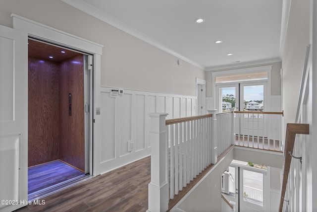 hallway with wood finished floors, a decorative wall, wainscoting, ornamental molding, and an upstairs landing