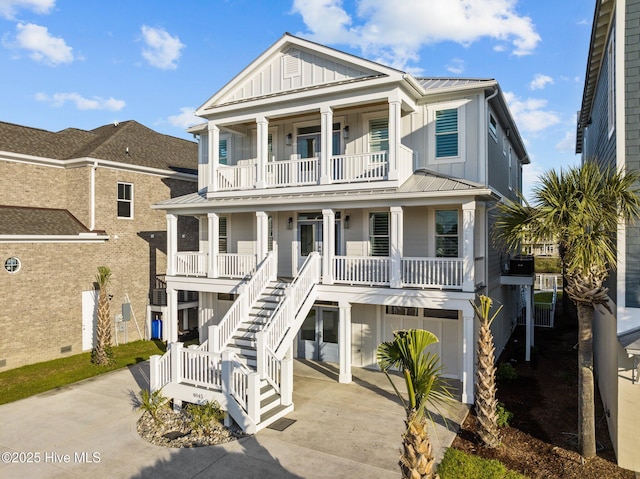 view of front of house featuring board and batten siding, stairs, a balcony, a standing seam roof, and covered porch