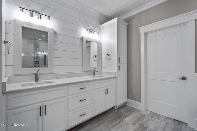 bathroom with double vanity, wood finished floors, baseboards, and a sink