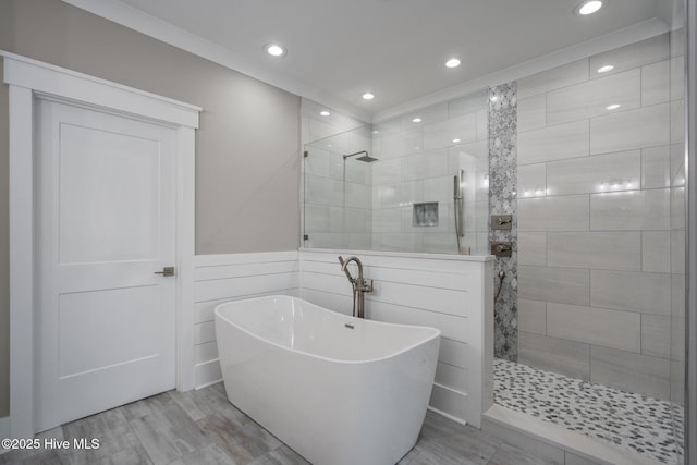 bathroom featuring recessed lighting, a walk in shower, a wainscoted wall, and a freestanding bath