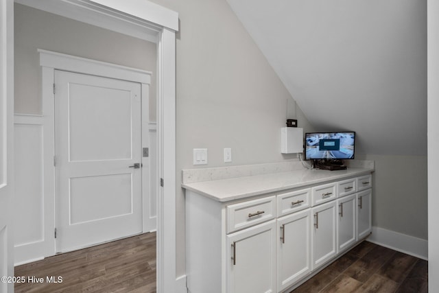 interior space featuring dark wood-style floors, white cabinets, light countertops, and vaulted ceiling