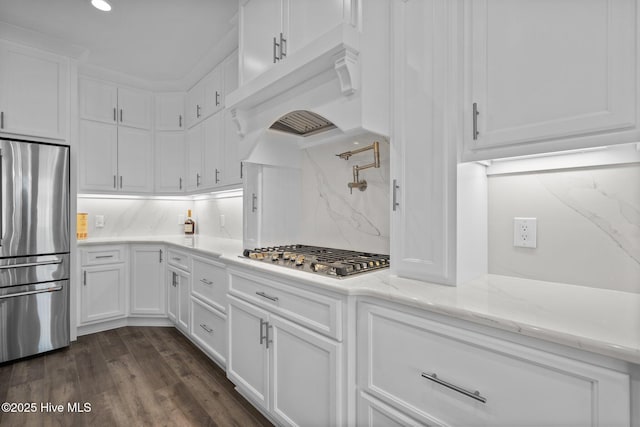 kitchen with appliances with stainless steel finishes, dark wood-style flooring, white cabinetry, and light stone countertops