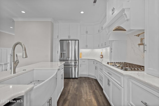 kitchen with light stone countertops, a sink, stainless steel appliances, visible vents, and white cabinetry