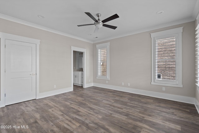 unfurnished bedroom featuring crown molding, ensuite bath, dark wood finished floors, and baseboards