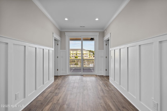 interior space featuring crown molding, a wainscoted wall, recessed lighting, dark wood-type flooring, and a decorative wall