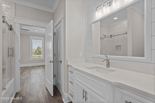 bathroom with baseboards, recessed lighting, a shower with shower door, wood finished floors, and vanity