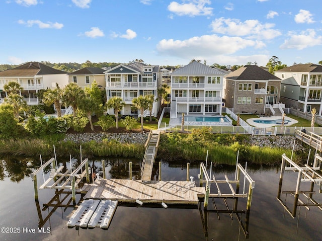 dock area with boat lift, a residential view, a water view, and an outdoor pool