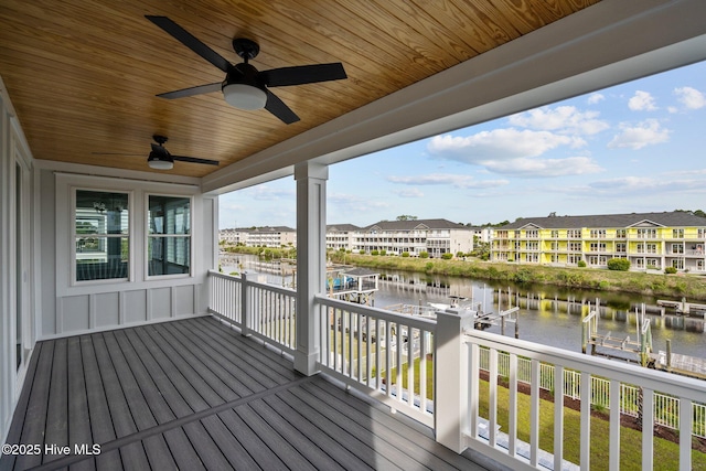 wooden deck with a residential view, a water view, a boat dock, a ceiling fan, and boat lift