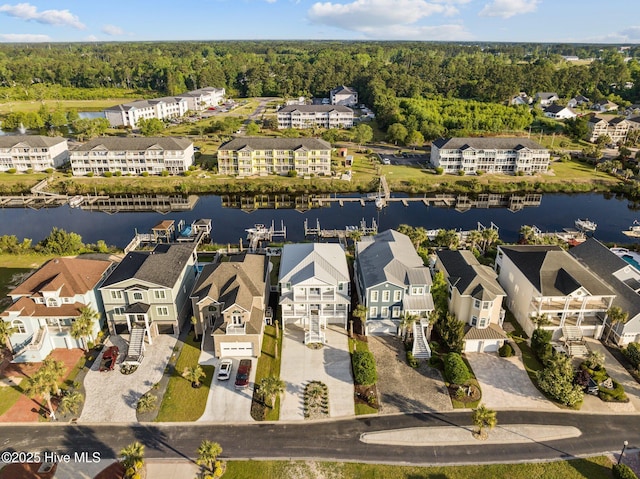 drone / aerial view featuring a wooded view, a residential view, and a water view