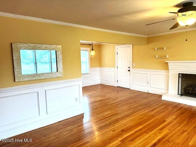 407 Main St, Bayboro, NC 28515 - unfurnished living room featuring crown molding, wainscoting, a ceiling fan, and wood finished floors