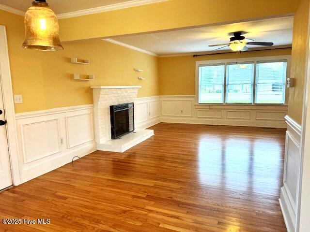 407 Main St, Bayboro, NC 28515 - unfurnished living room featuring ornamental molding, a decorative wall, wood finished floors, and a fireplace