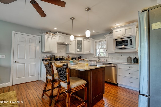 kitchen with hardwood / wood-style floors, stainless steel appliances, ceiling fan, and white cabinetry